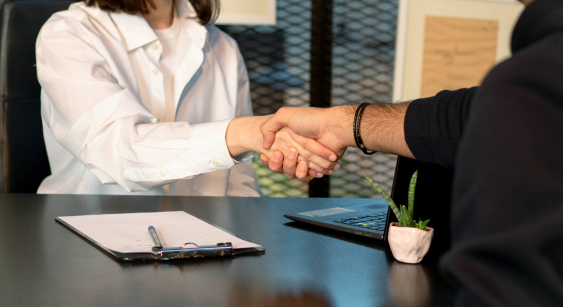 Poignée de main entre deux personnes au-dessus d'un bureau professionnel, symbolisant un accord ou un partenariat d'entreprise.
